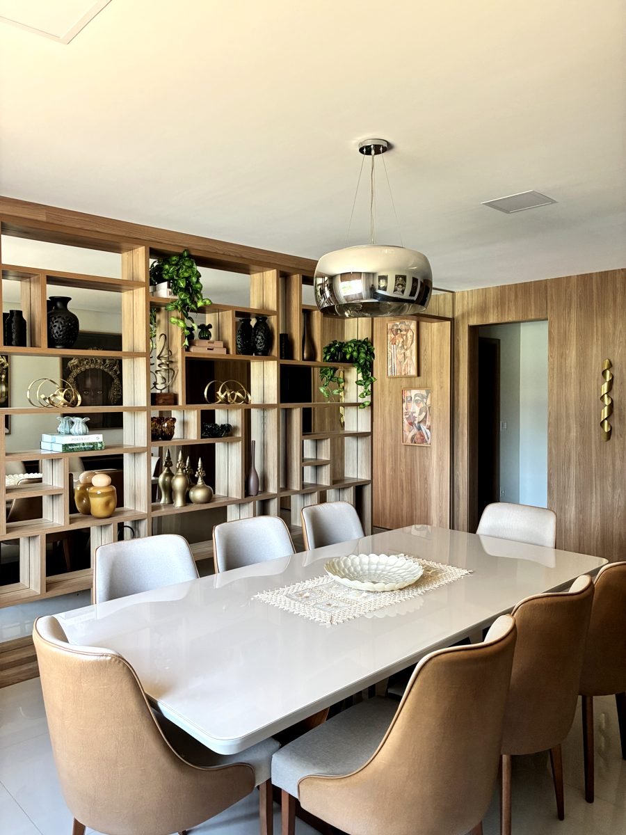 Sala de jantar com estante divisória e painel em madeira sob medida